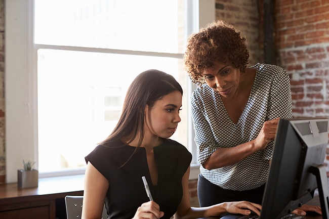 Two women chatting around computer