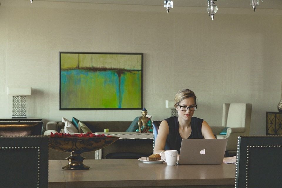 Businesswoman seated at a table using a laptop to learn when to use a journal entry with QuickBooks