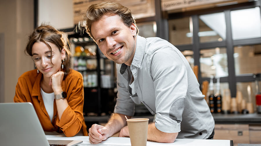 A person and person sitting at a table with a cup of coffee.