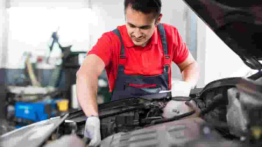 A person in a red shirt working on a car.