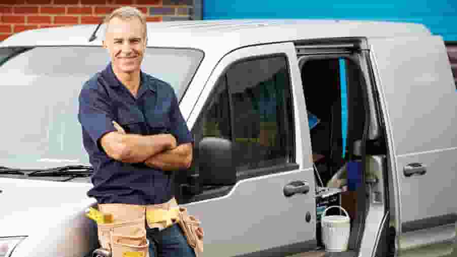 A person in a blue shirt and black pants standing next to a van.