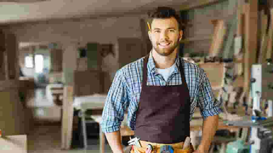 A person in a blue shirt and apron smiles.