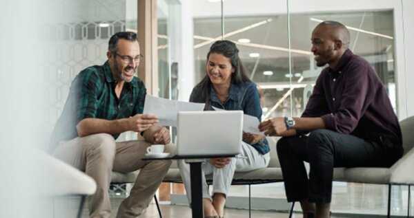 A group of people sitting around a table with laptops.