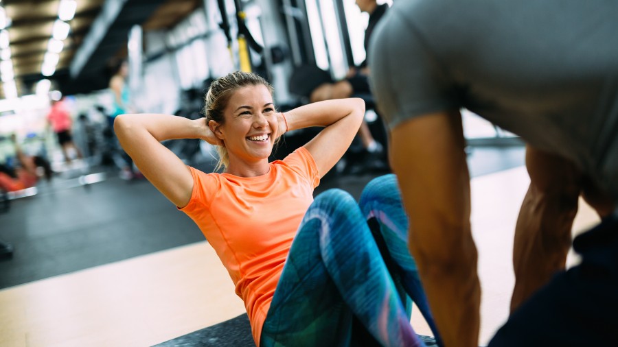Young woman doing exercises with personal trainer