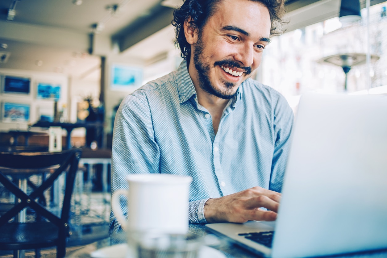 Accountant in cafe smiling at computer screen