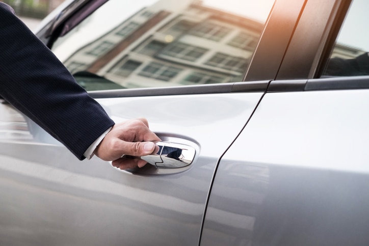 Businessman pulling car door open