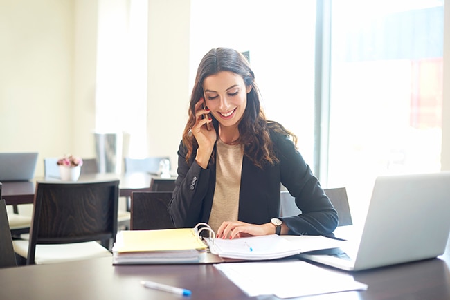 Shot of a young businesswoman sitting at office desk in front of laptop and making call