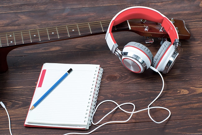 Notepad, guitar and headphone on a wooden floor