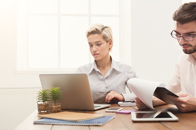 Man and woman working at a desk with laptop