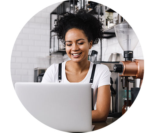 A smiling small business owner on a laptop utilising QuickBooks Beam to streamline payroll