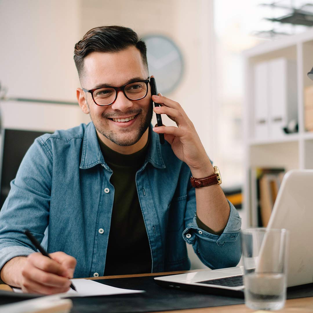 A person sitting at a table talking on a cell phone.