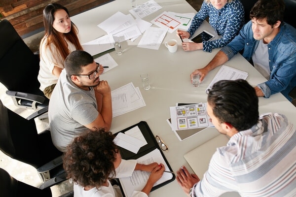 A group of people sitting around a table working on papers.