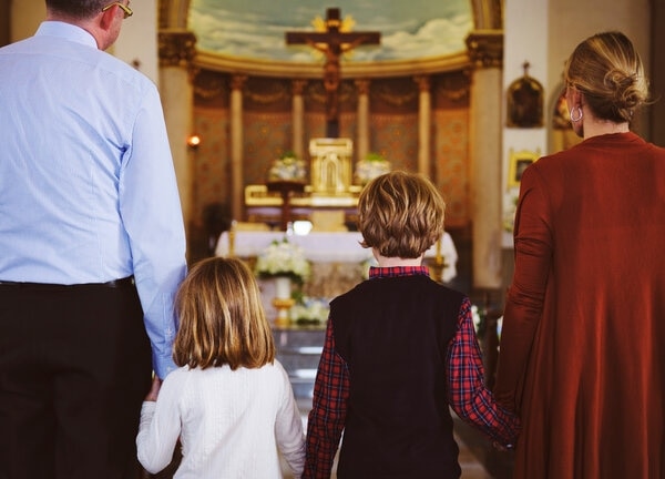 A group of people sitting at a table with a cross.