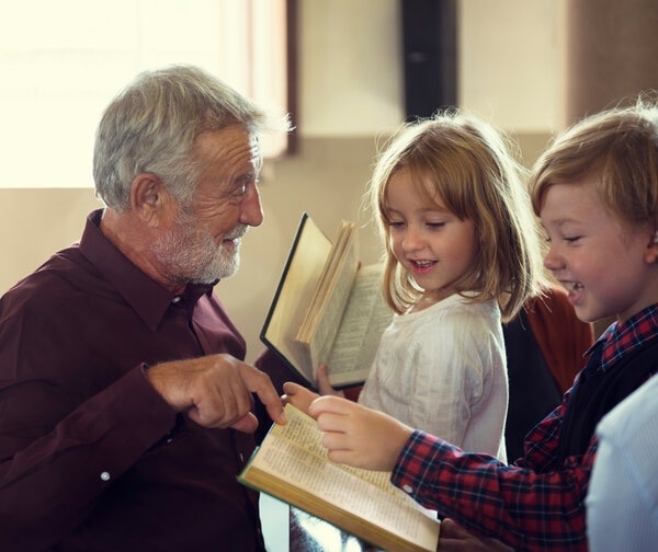 An older person and a young person are looking at a laptop.