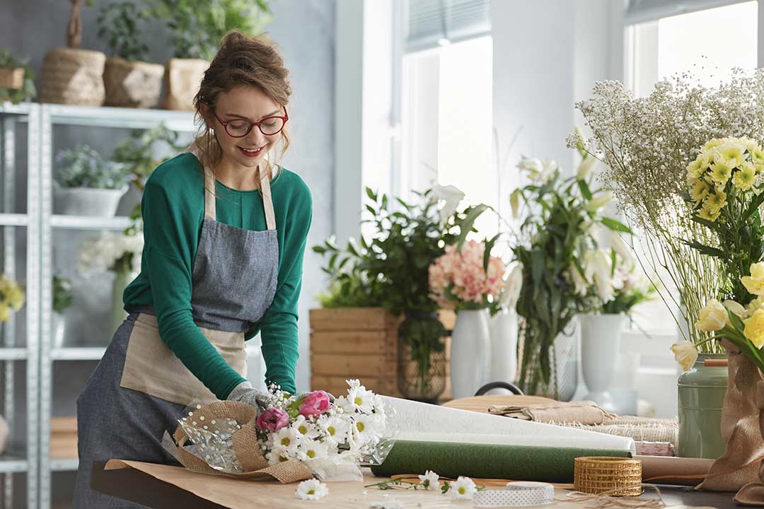 A person is preparing a vase of flowers.