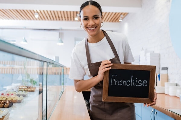 A person smiles as she holds a tray of apples.