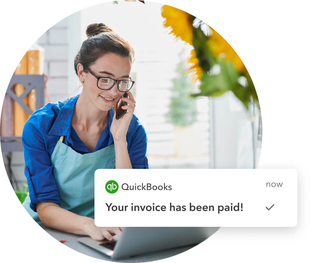 Small business owner smiling after receiving a notification of a paid invoice on QuickBooks