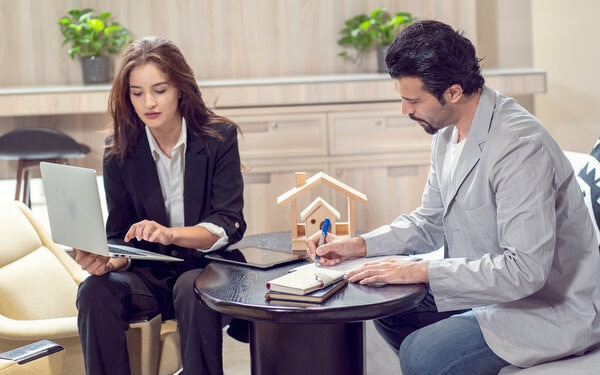 A person and person sitting at a table with a laptop.