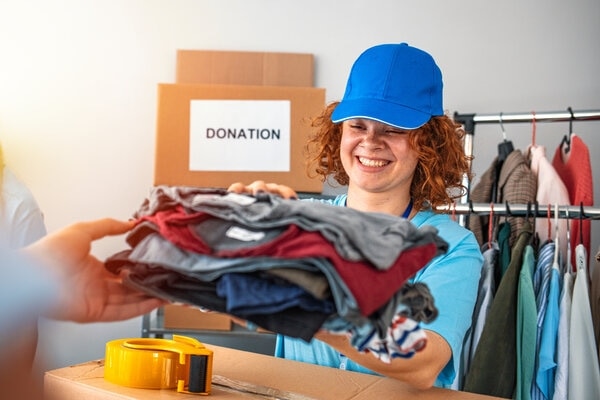 A person is packing a suit case with a hat on.