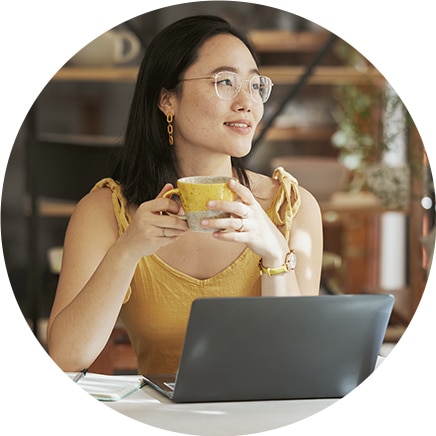 A small business owner relaxing in the coffee shop with a laptop nearby after using QuickBooks Payroll Software to automate calculations