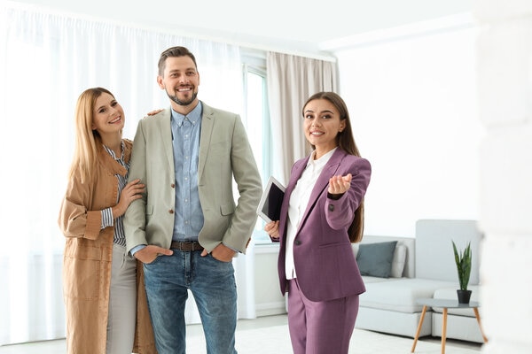 Three people in suits and ties standing in a living room.