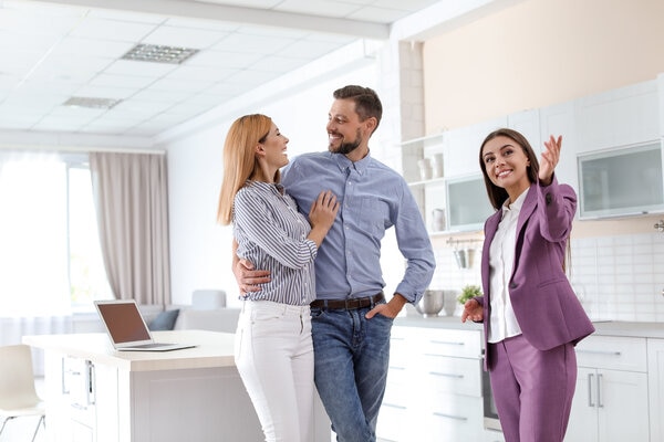 Three people are smiling and talking in a room.