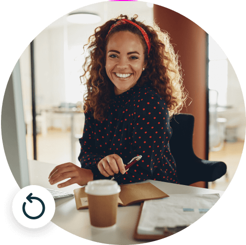 Woman smiling holding a pen sitting in an office