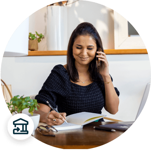 Woman smiling on the phone writing in a notebook