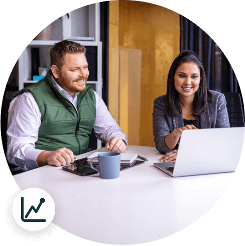 man and woman in office looking at laptop and smiling