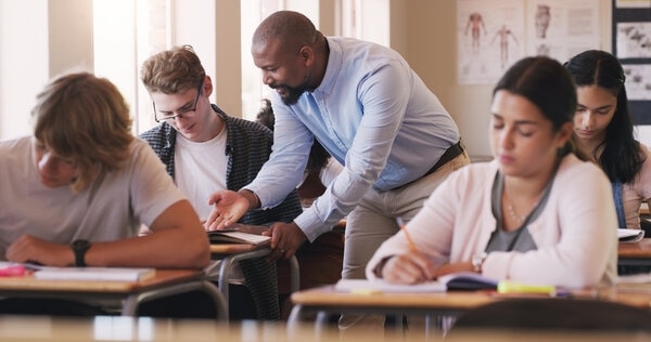 A group of people sitting around a table with laptops.