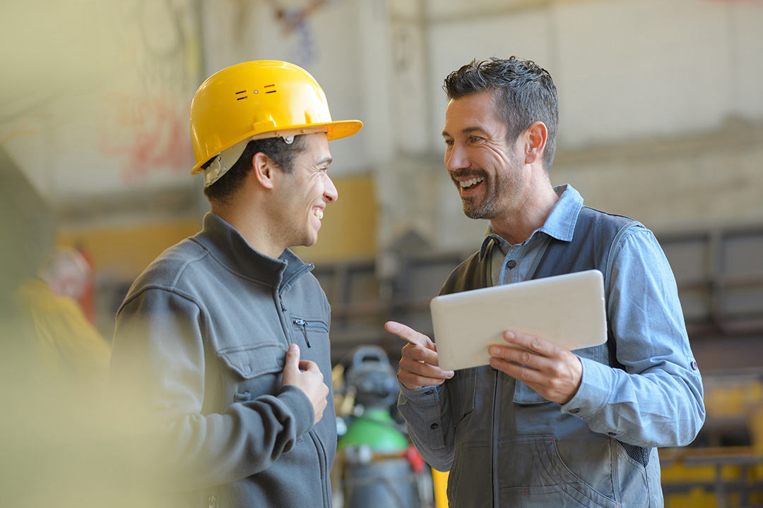 Two people smile as they talk to each other.