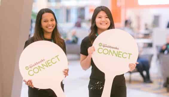 Two women holding Quickbooks Connect signs