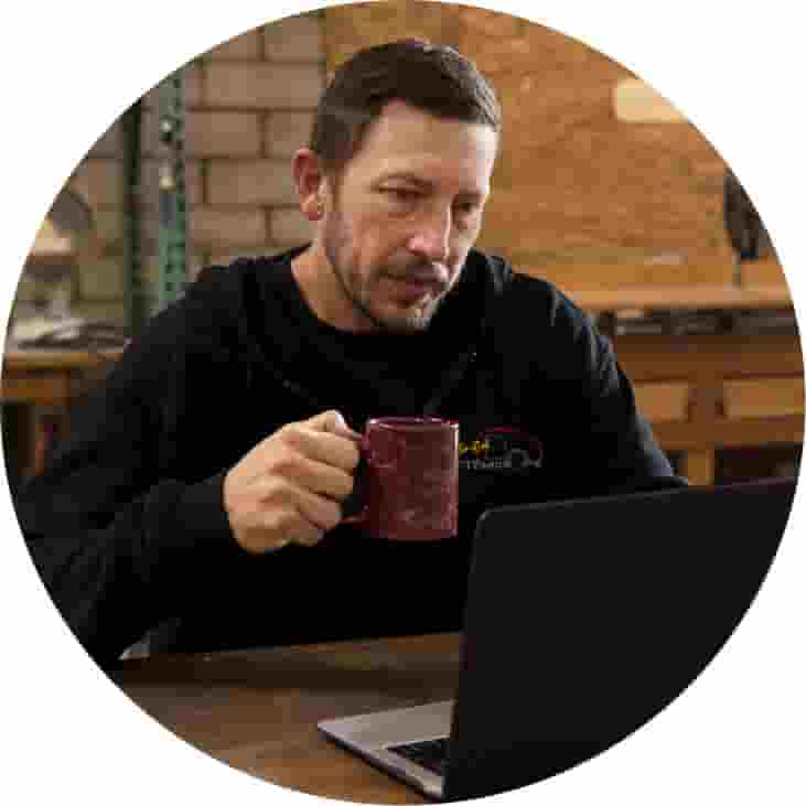 A person with a cup of coffee and a laptop.