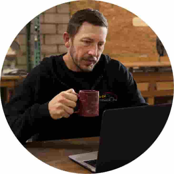 Person using QuickBooks Online on laptop while enjoying a cup of coffee