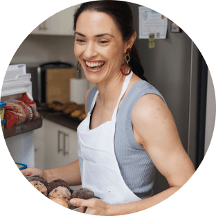 Brooke Alexander smiling while holding a tray of muffins in a QuickBooks promotional photo