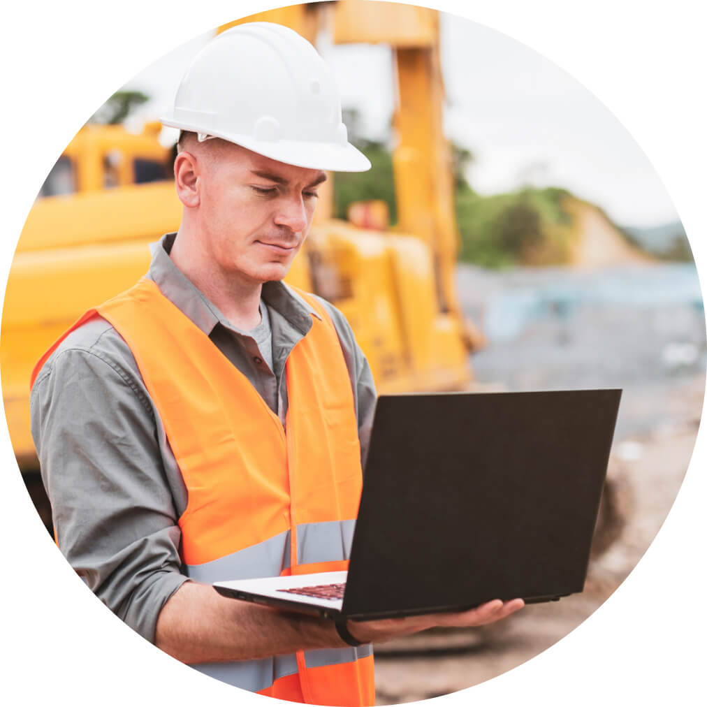 Construction worker on laptop using QuickBooks with build site in background
