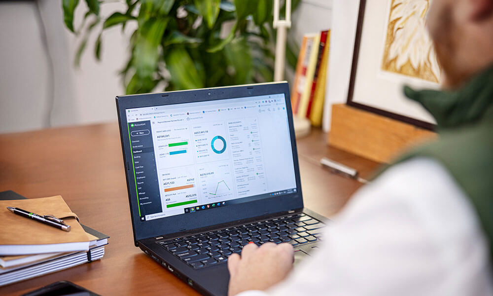 Man at desk using laptop with QuickBooks dashboard