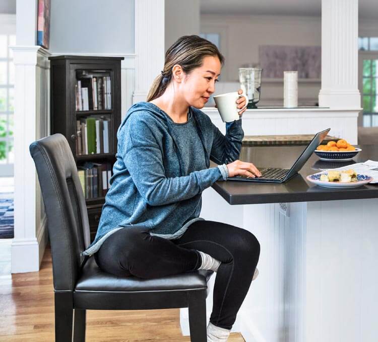 A person sitting at a table with a laptop computer.