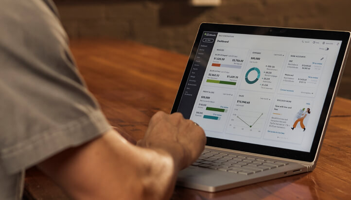 Person using laptop with QuickBooks Online dashboard showing