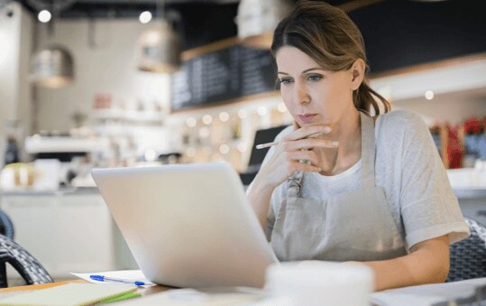 Quickbooks cloud accounting software being used by a small business owner at a cafe on her laptop