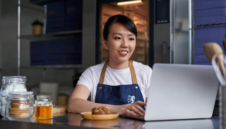 Small business owner smiling while using QuickBooks on laptop to manage suppliers