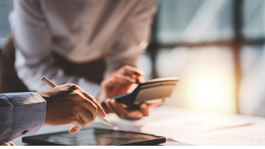 A person sitting at a desk with a laptop and mobile phone.