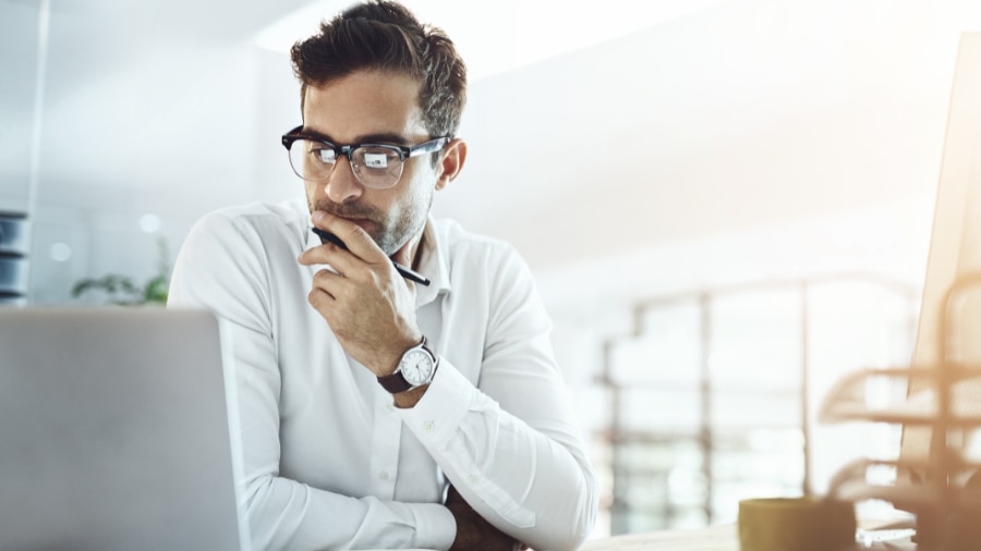 A person wearing glasses looking at a laptop.