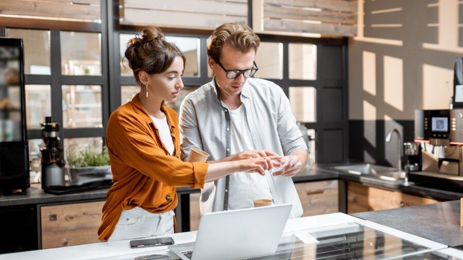 Two people looking at a laptop computer and have a discussion.