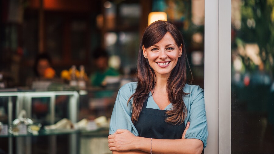 A woman smiling  in front of a store 