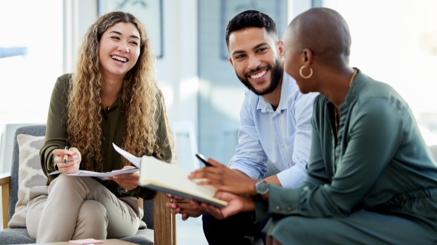 A group of people sitting around a table together, looking happy.