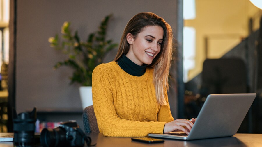 A woman sitting at a desk typing on a laptop.