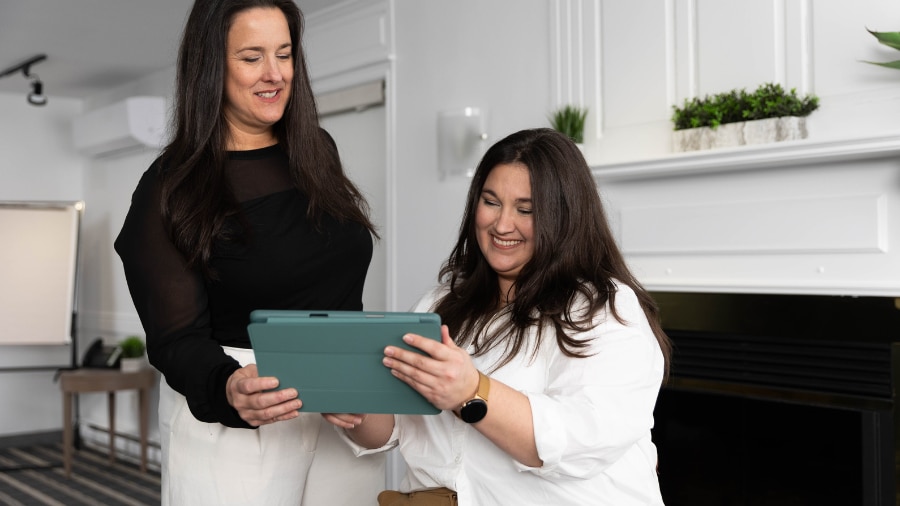 Two women holding a tablet and looking at it