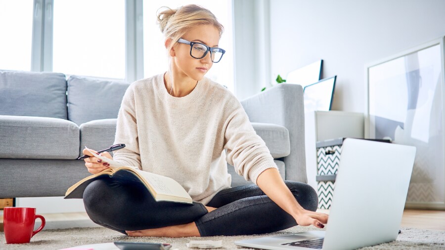 A person sitting in a living room working on a laptop.