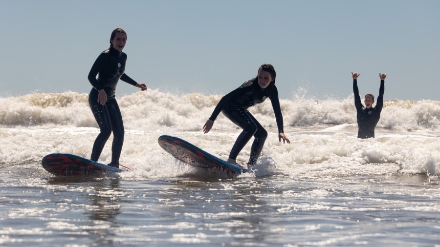 Two people in wet suits are surfing on a wave.